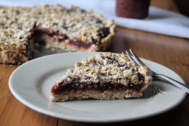 A slice of gluten-free jam tart on a plate with a fork.