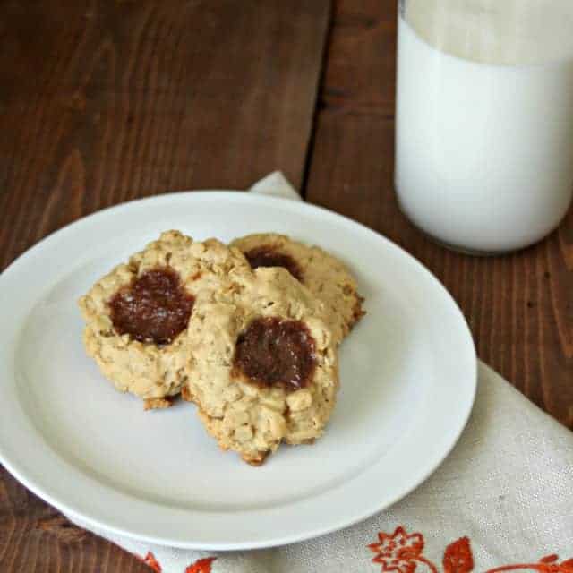 Peanut Butter and Jelly Thumbprint cookies on a plate with a glass of milk.