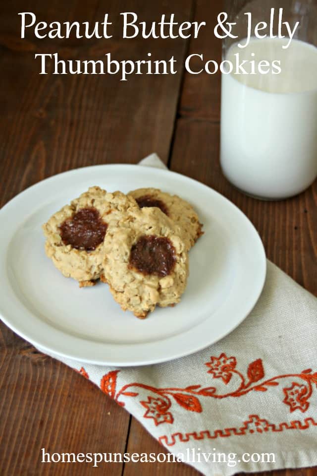 Peanut Butter and jelly thumbprint cookies on a plate with a glass of milk.