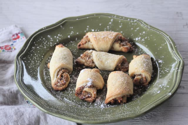 Potica cookies on a green plate sprinkled with powdered sugar.