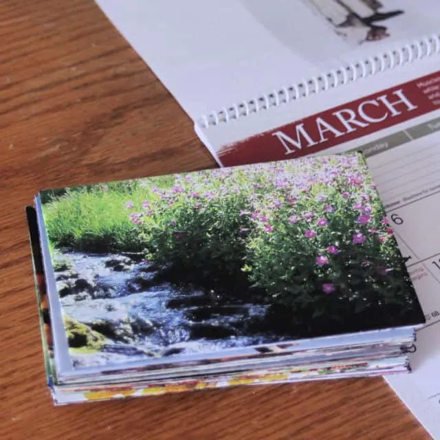 A stack of homemade envelopes sitting on top of an open calendar displaying the month of March.