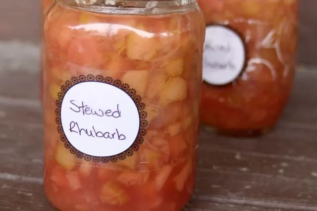 Jars of labeled stewed rhubarb on a wood table.