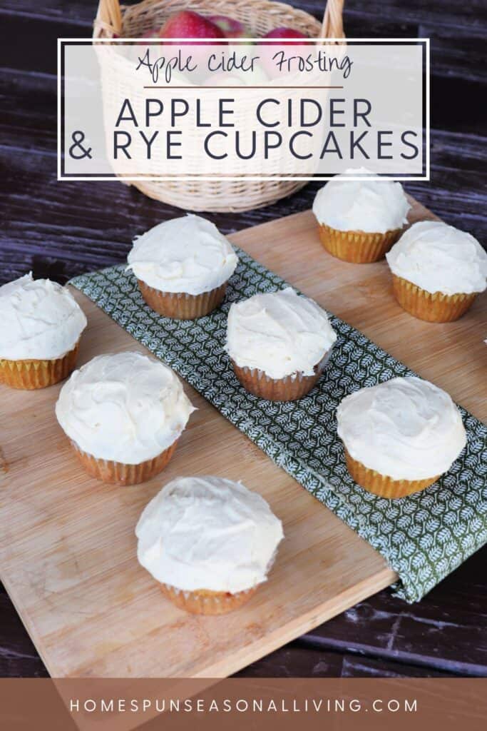 Frosted cupcakes sit on a wooden board. Text overlay reads: Apple Cider Frosting: Apple Cider & Rye Cupcakes