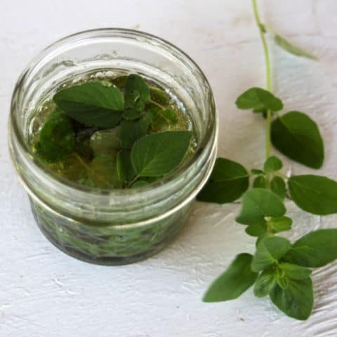 Oregano leaves infusing in a jar of honey.