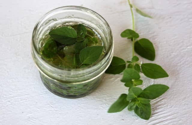 Oregano leaves infusing in a jar of honey.