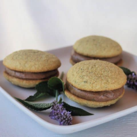 Anise hyssop whoopie pies on a plate with sprigs of fresh anise hyssop.