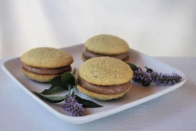 Anise hyssop whoopie pies on a plate with sprigs of fresh anise hyssop.