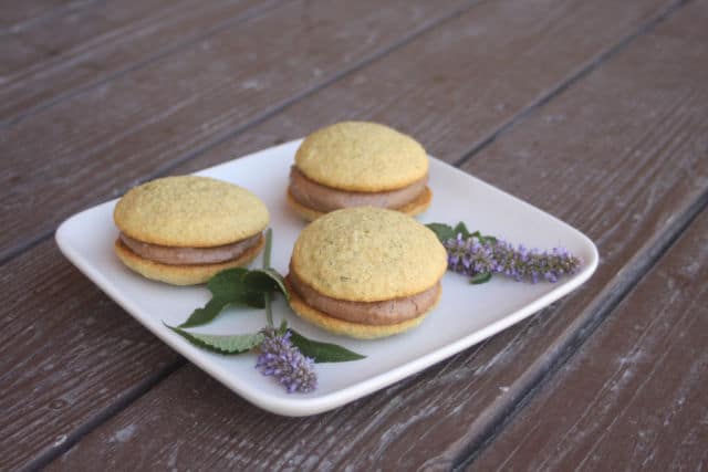 Anise hyssop whoopie pies on a plate with sprigs of fresh anise hyssop.