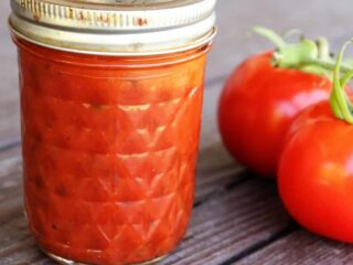 A jar of pizza sauce sitting next to fresh tomatoes.
