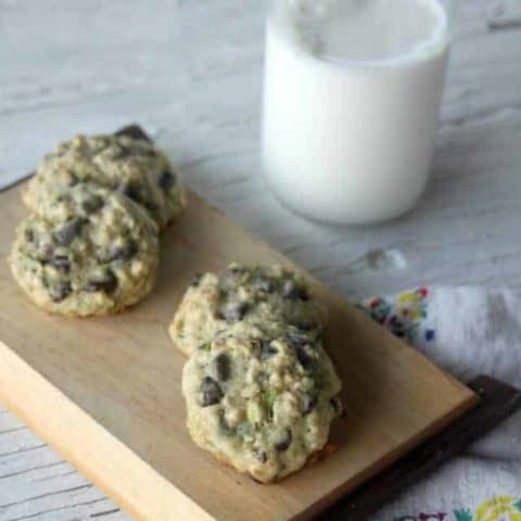 Zucchini Oat Chocolate Chip Cookies on a wooden platter with a glass of milk.