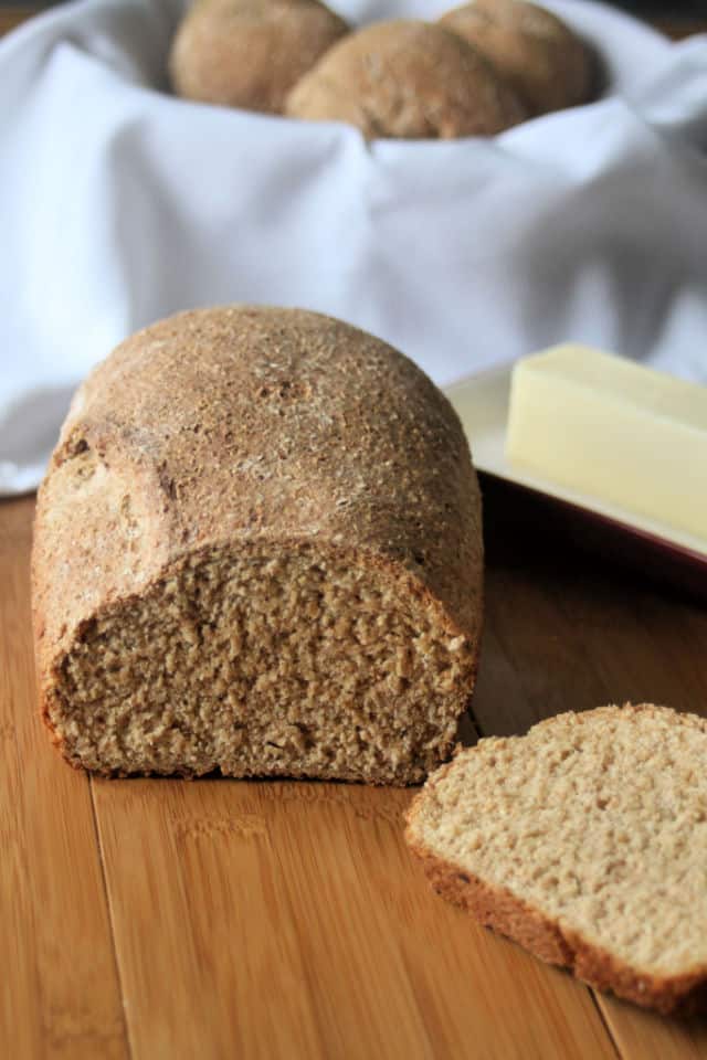 A garlic herb bread that's been sliced with a stick of butter behind it.