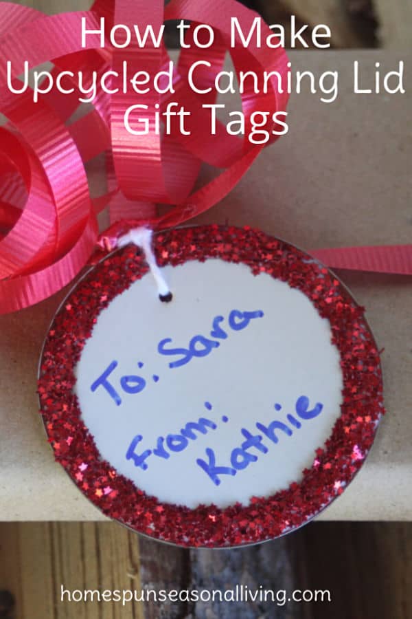 An upcycled canning lid gift tag attached to a wrapped gift with red ribbon.