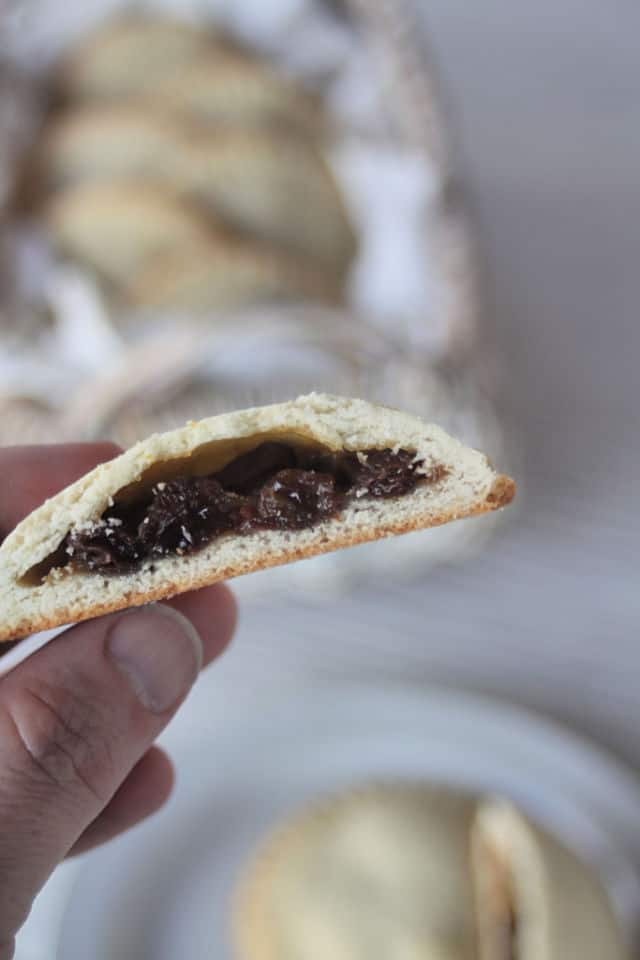 A hand holding a rum raisin filled cookie cut in half.