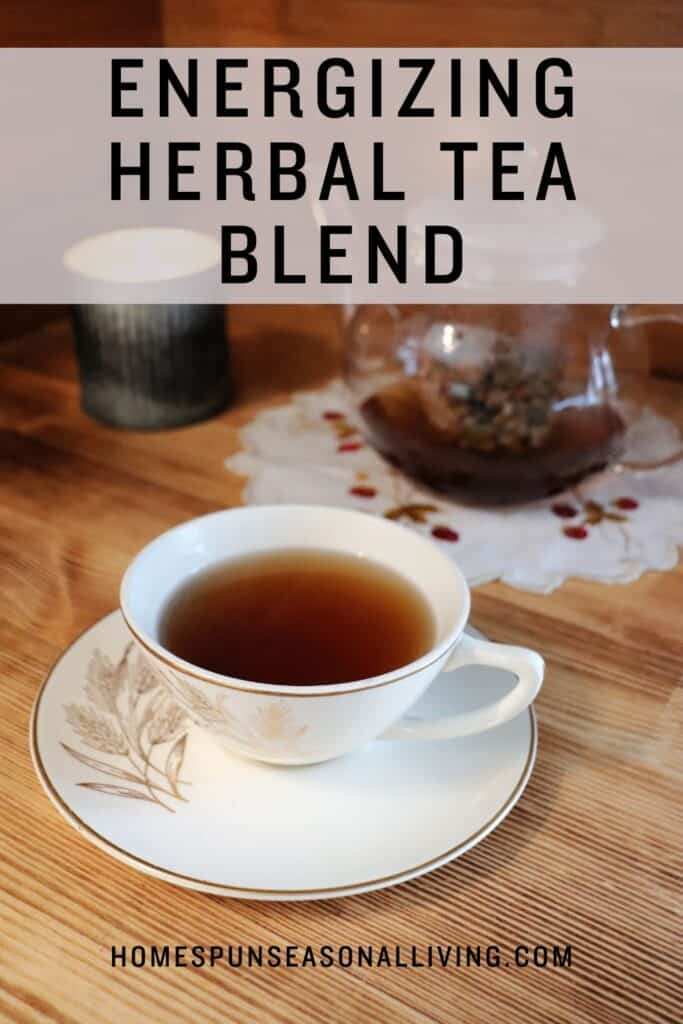 A tea cup sits on a saucer and is full of dark tea. In the background a clear glass tea pot sits on a cloth next to a glowing candle. Text overlay reads: Energizing Herbal Tea Blend. 