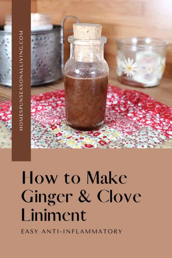 A small glass bottle with a cork lid is full of a dark liquid. The bottle sits on a quilted square of red and yellow colors. Candles sit in the background. Text overlay reads: how to make ginger and clove liniment. Easy anti-inflammatory.