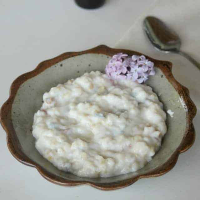 Lilac rice pudding in a bowl with lilac garnish.