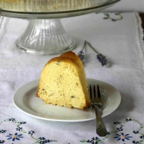Slice of lavender bundt cake on a cloth covered table.
