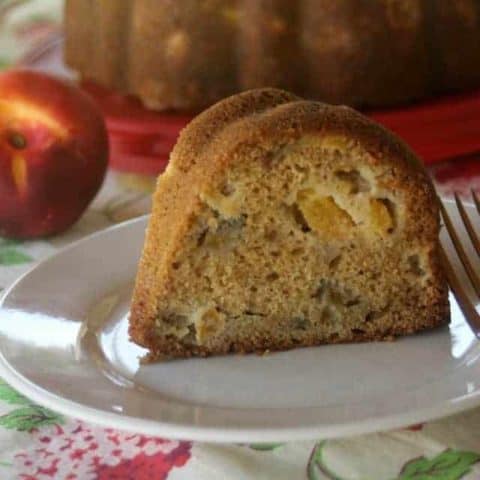 Slice of nectarine cake on a plate with a fork.