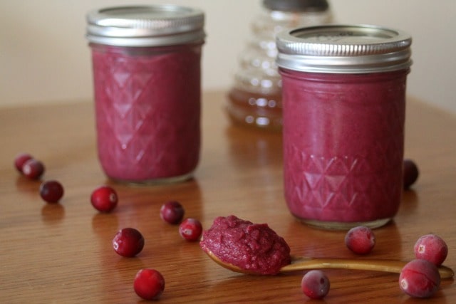 Jars of cranberry honey mustard on a table with some sitting on a spoon.