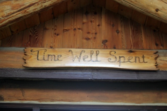 A wooden sign stating 'time well spent' hung above a cabin door.