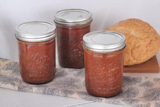 Jars of canned sloppy joe filling in front of a loaf of bread.