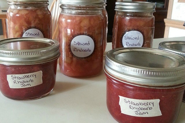 jars of strawberry rhubarb jam and stewed rhubarb on the kitchen counter.