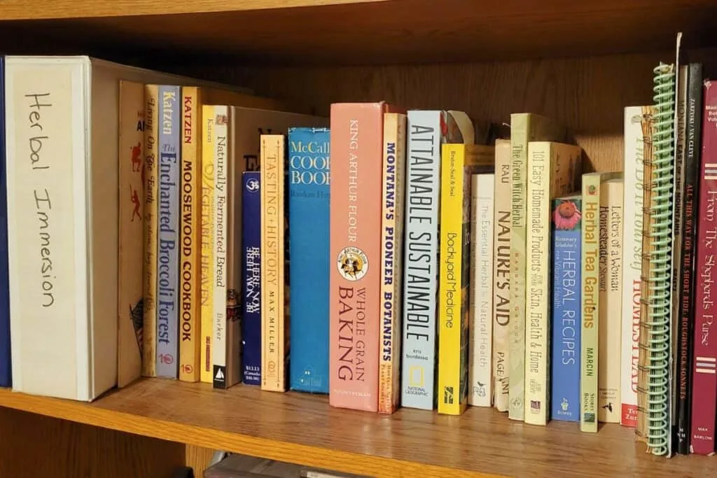 A wooden bookshelf is full of books and binders on various topics. 