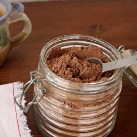 homemade hot cocoa mix in a jar with silver measuring spoon inside.