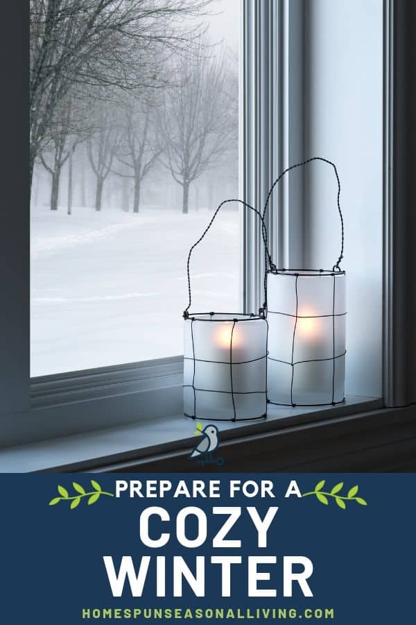 Candles in a lantern on a windowsill looking outside to a snow covered landscape.