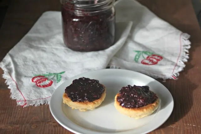 Cherry coconut compote on cookies with jar in background.