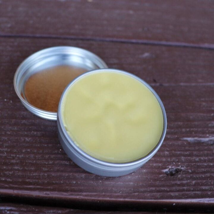 An open tin container sits on a table showing the herbal salve inside.