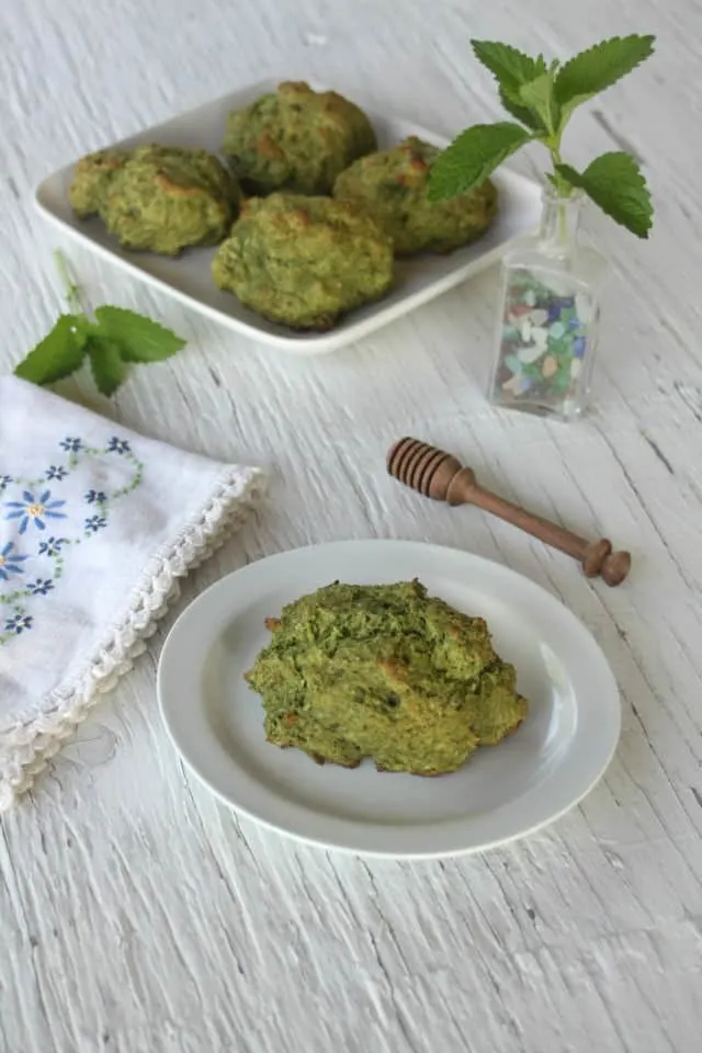 lemon balm drop biscuits on a table with napkin and vase of fresh lemon balm leaves.