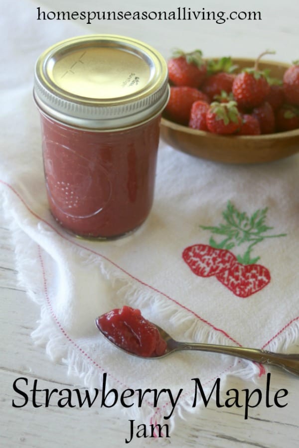 A jar of strawberry maple jam with some jam on a spoon.