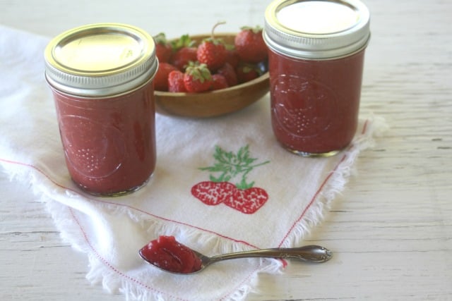 2 jars of strawberry maple jam on a napkin with some jam in a spoon.