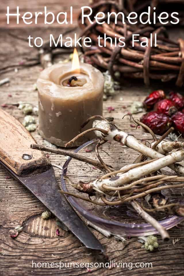 A knife and lit candle on a table with medicinal roots and rose hips.