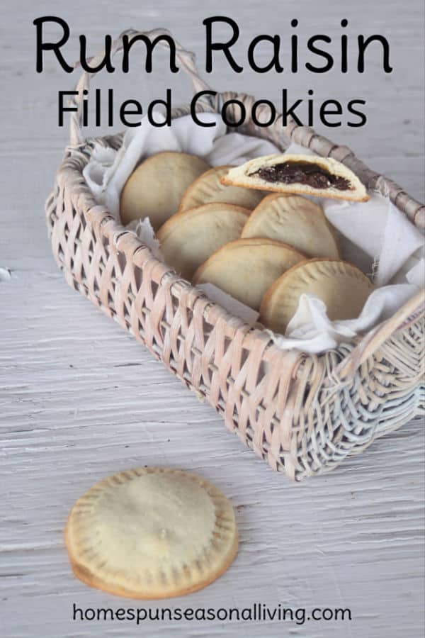 A rum raisin filled cookie sitting on a table in front of a basket full of cookies.