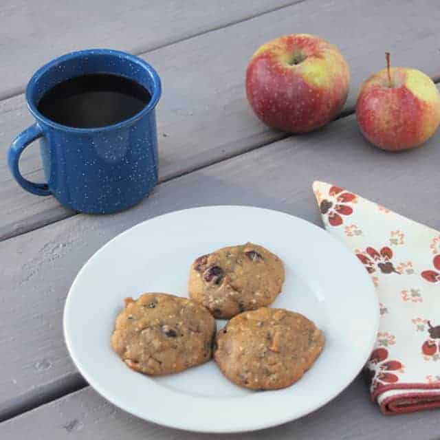 Soft spiced coffee cookies on a plate with cup of coffee, fresh apples, and a cloth napkin.