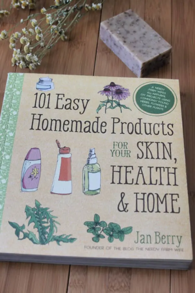 The book 101 Easy Homemade Products on a table with a bar of soap and dried herbs.