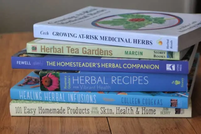 A stack of herbal books on a table.