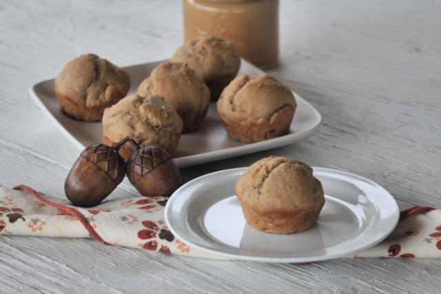 Applesauce muffin on a plate with a napkin and nuts.