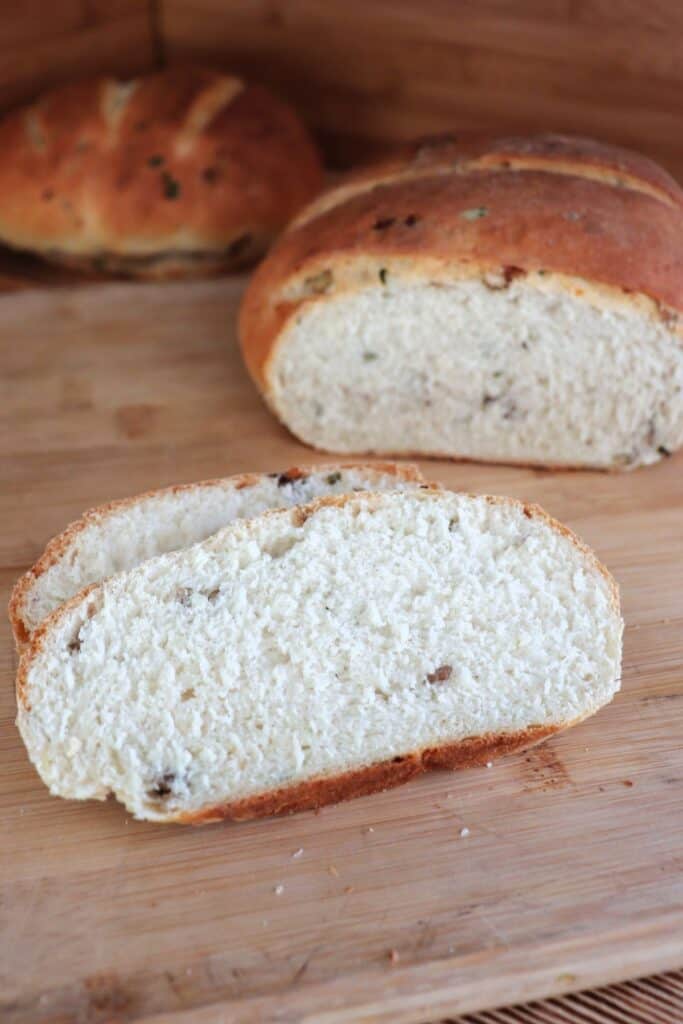 Slices of bread sit on a board with the remaining loaf in the background.