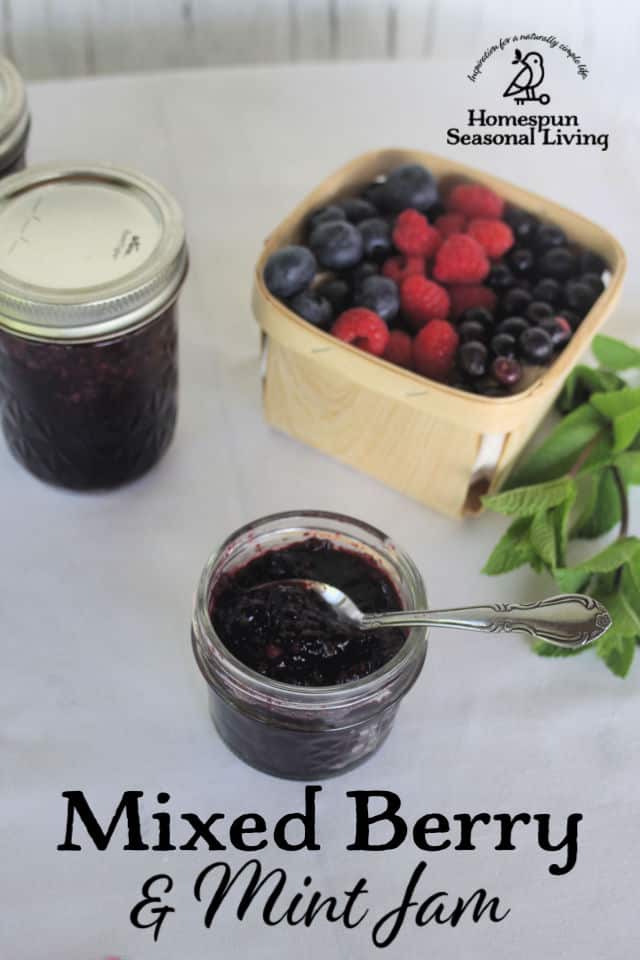 A spoon sticking out of an open jar of minted mixed berry jam.