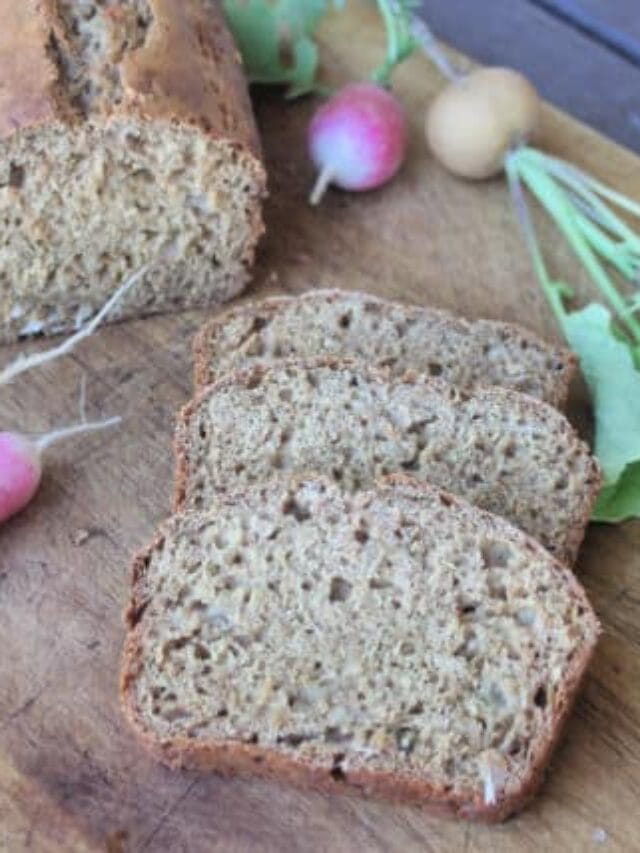 Slices of radish bread on a board with the loaf and fresh radishes.