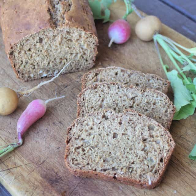 Radish bread slices on a cutting board surrounded by fresh radishes.