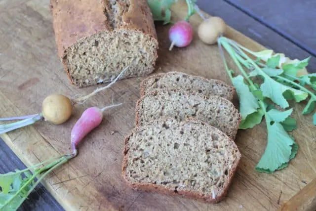 Radish bread slices on a cutting board surrounded by fresh radishes.