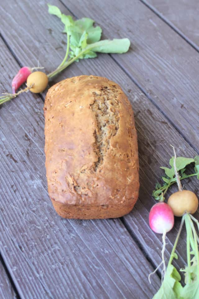 Radish bread loaf on a board surrounded by fresh radishes.