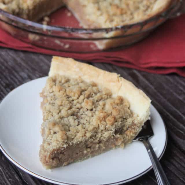 Apple butter pie with crumb topping slice on a plate with a fork.