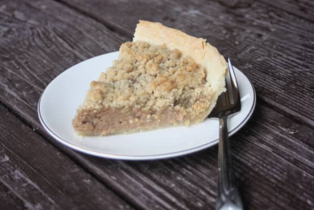 Slice of apple butter pie on a plate with a fork.