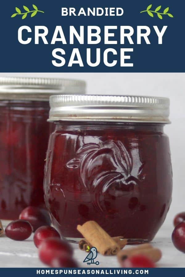 2 jars of brandied cranberry sauce on a table surrounded by cinnamon sticks and fresh cranberries with a text overlay.