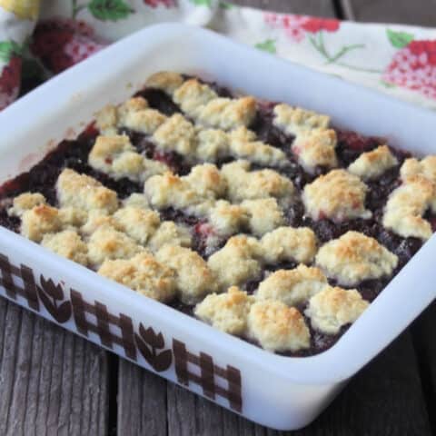 Chocolate cranberry bars in a white baking pan on a table with a napkin.